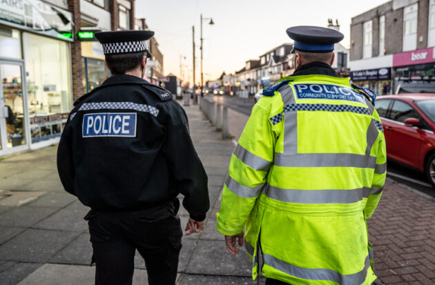 2 police officers walking up a street