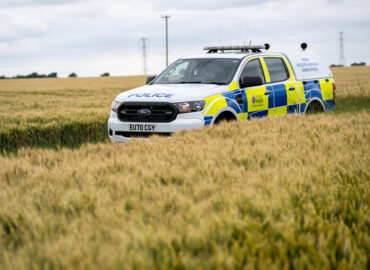 An off road Essex Police livered vehicle driving through a cornfield.