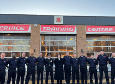 Eleven firefighters are lined up in front of the Service Training Centre building. Deputy PFCC Jane Gardner and Chief Fire Officer Rick Hylton are stood in the middle of the line up.